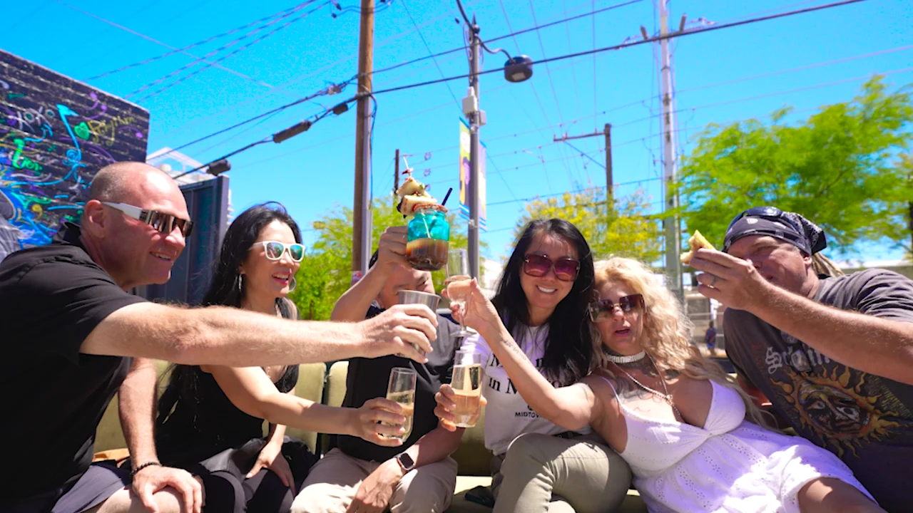 Friends raising drinks together on Audio Bar’s sunny courtyard patio