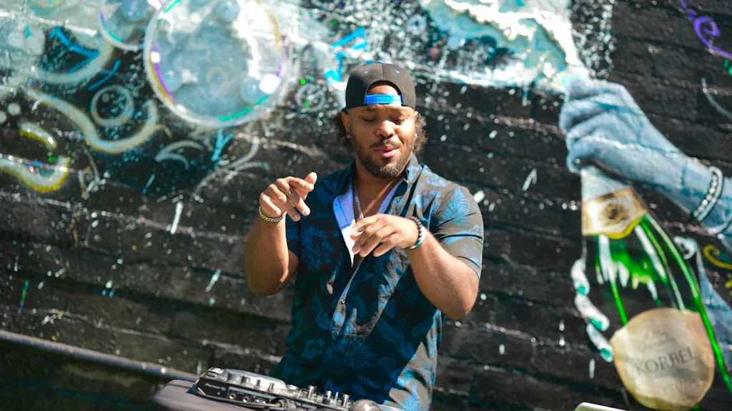 A daytime DJ at Audio Bar with the courtyard mural behind the decks